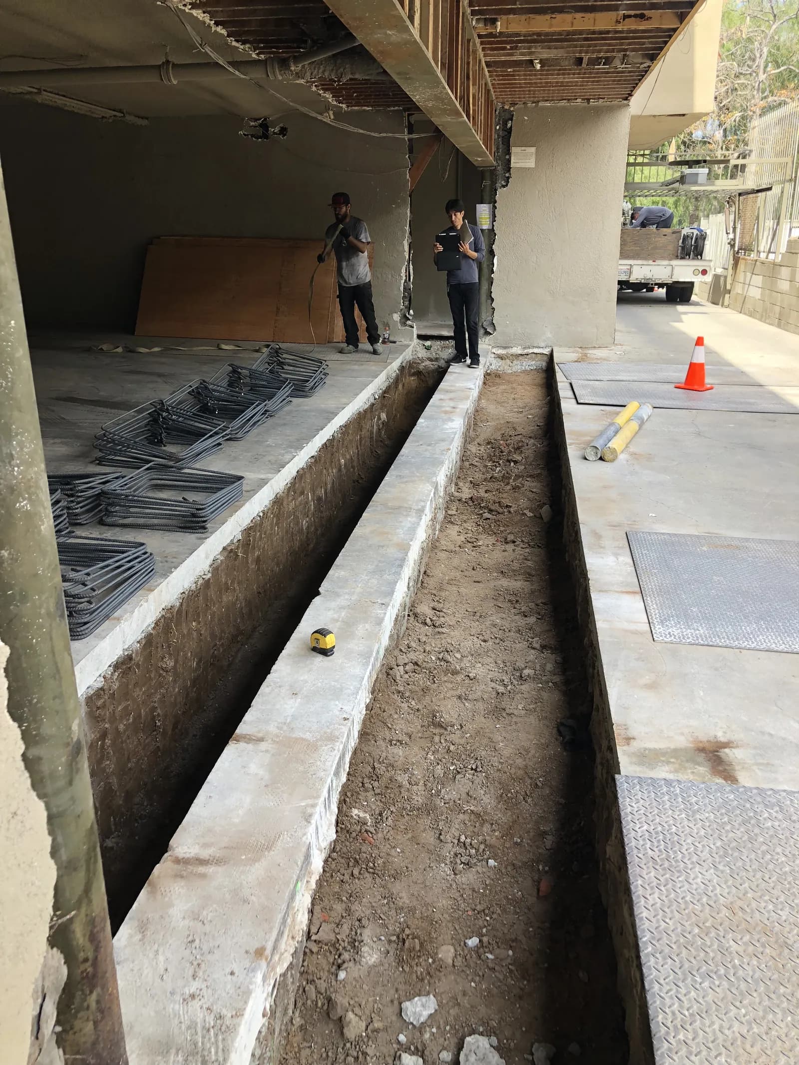 Excavated grade-beam trench and reinforcing steel prepared for concrete at a soft-story retrofit foundation.