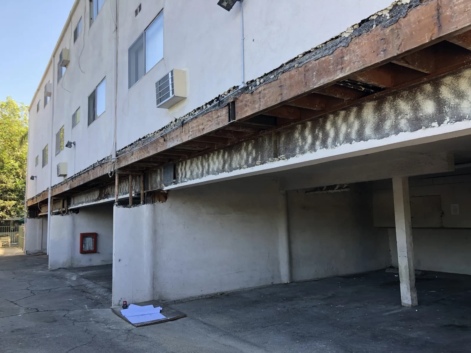 Elevated walkway with the soffit removed, exposing the framing before balcony repair and waterproofing.