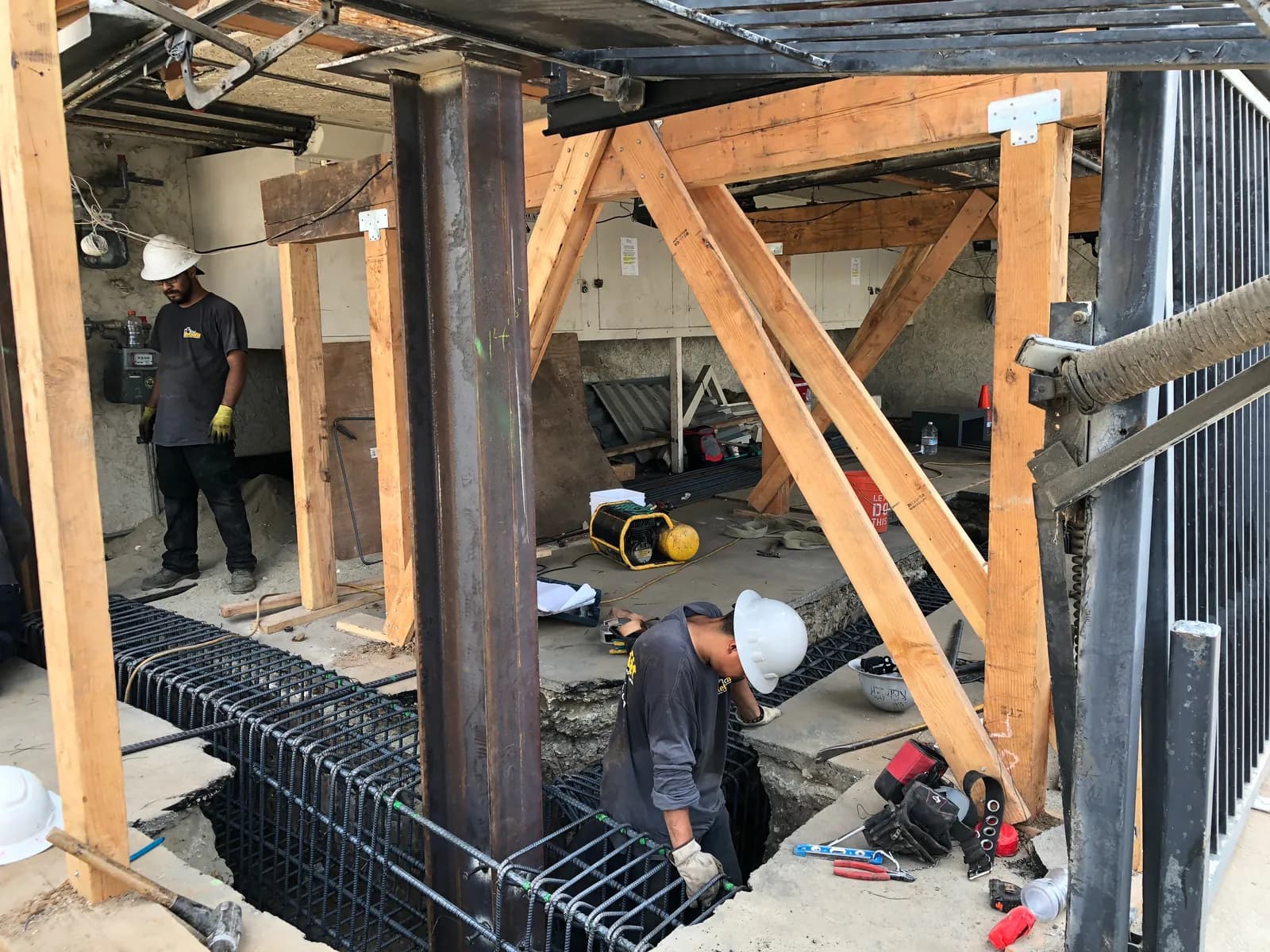 New steel column set on a reinforcing-steel footing cage during a soft-story seismic retrofit